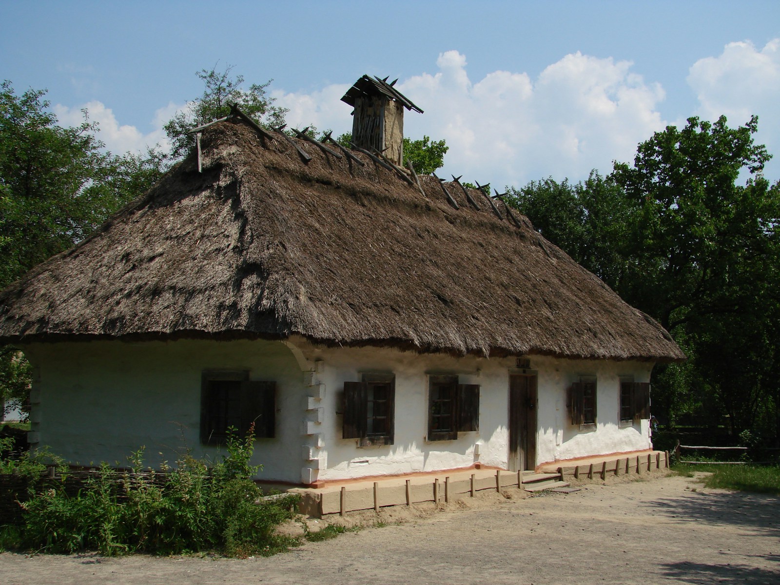 white and brown house near green trees under blue sky during daytime